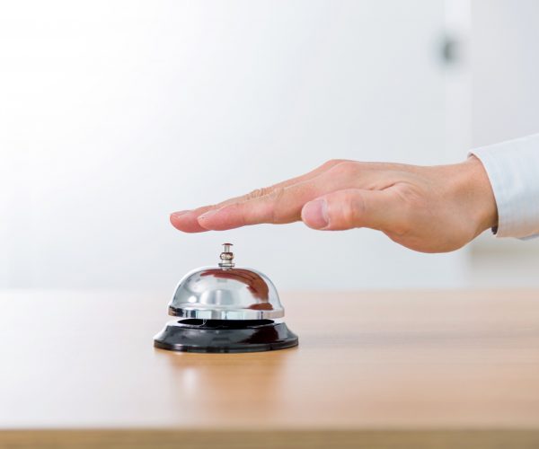 Businessman hand ringing the hotel service bell.